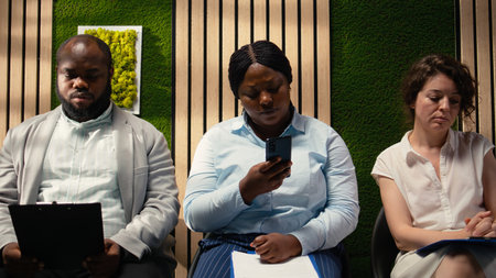 Relaxed female applicant browses phone in hallway lineup and waiting, repeating her speech to...