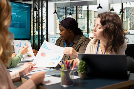 Multiethnic manager and her team review analytics and build a vision in a bright and strategic work environment, aligning corporate objectives with career progress and overall growth.の写真素材