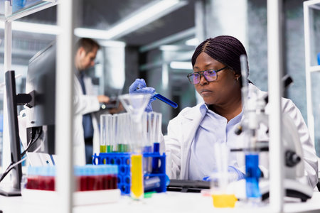 African american expert working for bioscience with modern lab tools, conducting experiment and...