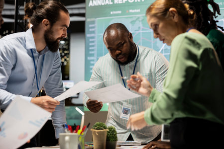 Diverse coworkers team participating in a late night briefing session, exchanging documents and...