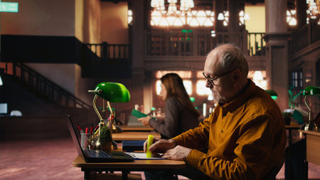 Elderly man highlighting important ideas from coursework papers, reading and studying in a campus...
