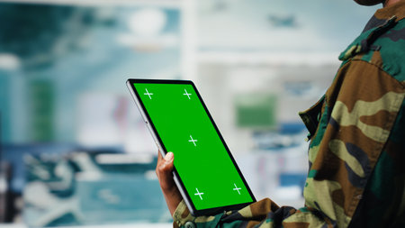 Isolated screen tablet app used by soldier in war room to operate CCTV gear. Army operator using chroma key device to deploy electronic warfare tools used to disrupt enemy communications, camera Bの写真素材