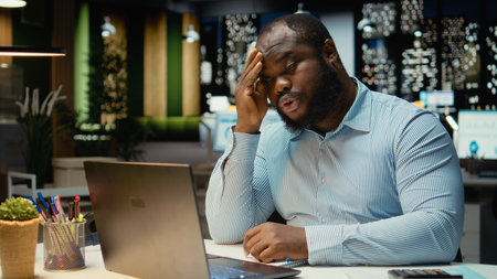 Black troubled worker rubbing his head in frustration and weariness, expressing fatigue and...