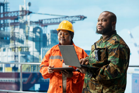 Army soldier protecting offshore rig next to employee monitoring operations on oil platform deck....