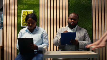 African american applicants filling in registration forms for job interview and open position, ensuring successful recruitment and meeting with the HR. Writing down qualifications. Camera A.の写真素材