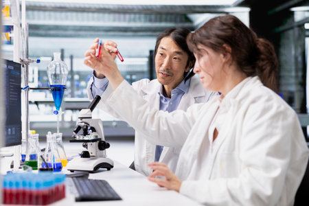 Molecular biologists in lab inspecting blood samples in test tube, looking for breakthroughs during clinical trials. Research facility workers comparing sanguine fluid vials, doing RDの写真素材