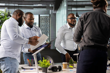 Diverse coworkers in meeting discuss strategy and budgeting, forecasting plans for efficiency. Corporate team evaluates performance metrics, reports and files for resources allocation.の写真素材