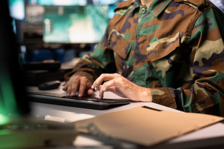 Air force combat control officer typing on keyboard, performing tactical level surveillance, close up. Military specialist using radar to search for potential assault zones, inputting coordinatesの写真素材