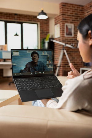Self employed woman using laptop for video call, networking with male colleague about work strategy....