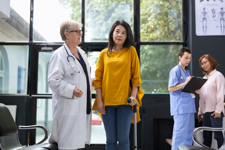 Doctor guiding patient with locomotor disability while using crutches for physical support in healthcare setting. Recovery journey includes walking exercises and professional advice.の写真素材