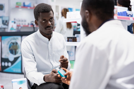 Black pharmacist using glucometer for sugar level measurements, checking the insulin levels and ensuring diabetic care in busy drugstore space. Specialist does health consultation.の写真素材