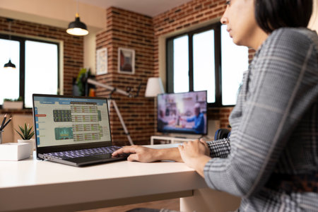 Focused female accountant works from home, using laptop to analyze company statistics and monitor...