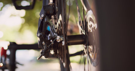 Close-up shot of various bicycle parts like cassette, pulley wheel and rear derailleur being maintained outside. Detailed view of person adjusting broken bike wheel with specialized tool.の写真素材
