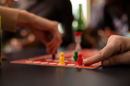 Closeup shot of caucasian finger moving a red piece on board. The image captures moment of strategic play during board game session, emphasizing detailed movement of the figurines.の写真素材