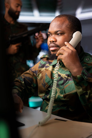 Intelligence agency expert using communication systems to call in air strikes on enemy troops. African american military dispatcher making phone call to request air support for ground soldiersの写真素材