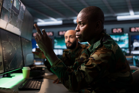 Army soldier managing air traffic control for military aircrafts, using radar surveillance. African american military agent following planes on reconnaissance satellite systemの写真素材