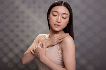 Asian woman with glowing skin showcasing self confidence for a skincare ad, gentle graceful presence with minimal makeup look for a beauty advertisement. Body positivity and self esteem.の写真素材