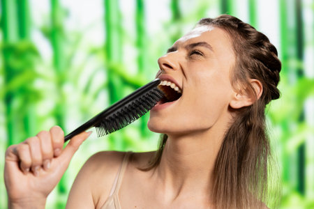 Joyful confident model singing with her hair brush and having fun, symbolizing self acceptance and...