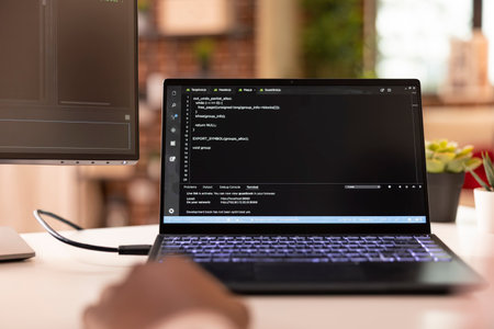 Closeup of laptop displaying code as african american developer troubleshoots app project from home....
