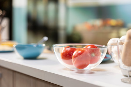 Empty kitchen with pizza ingredients laid out on a kitchen island. Bowl of tomatoes and sauce placed beside spices and utensils on the countertop, cozy space for homemade food preparation.の写真素材