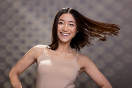 Positive asian person with radiant skin and soft candid smile posing in studio, advertising natural beauty and body positivity. Showing self acceptance with graceful energy and authenticity.の写真素材