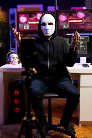 Hacker hidden in underground lair sending ultimatum to foreign governments, hacking systems. Masked...