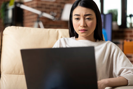 Serious female manager preparing business presentation from apartment, using digital device and online resources. Asian startup founder staying productive while working from home.の写真素材