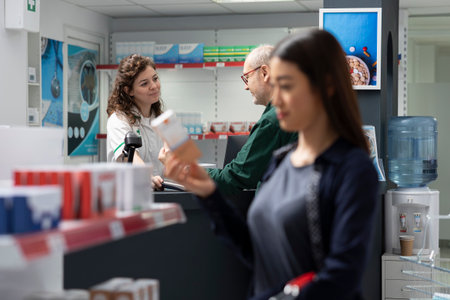 Old retired person paying for medicine with his smartwatch during pharmacy visit, professional healthcare worker supports POS terminal payment at the checkout counter. Retail service.の写真素材