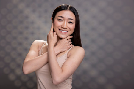 Portrait of a cheerful Asian model with graceful complexion and radiant skin, posing with self confidence. Vibrant femininity with natural no makeup aesthetic.の写真素材