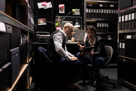 Older inspector and agent working together to study surveillance photos and clues, connecting...