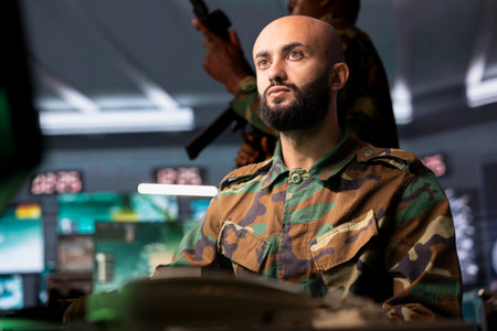 Soldier in base of operations analyzing aerial reconnaissance data to come up with warfare winning tactics. Intelligence corps agent controlling drones attacking strategic enemy targetsの写真素材