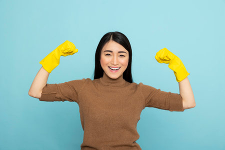 Cheerful asian housekeeper wearing rubber gloves and posing confidently after successful spring cleaning. Great for advertisements promoting proud service workers and empowered women.の写真素材