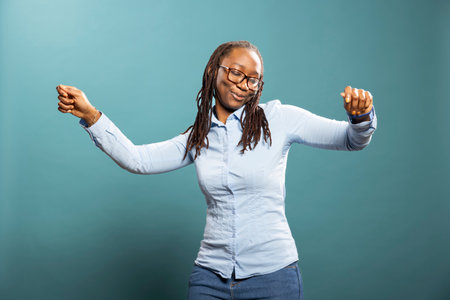 Portrait of charismatic african american woman enjoying music and movement in studio. Black female...