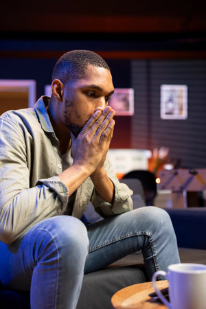 Worried stressed black guy experiences fatigue and frustration at home, working remotely and...