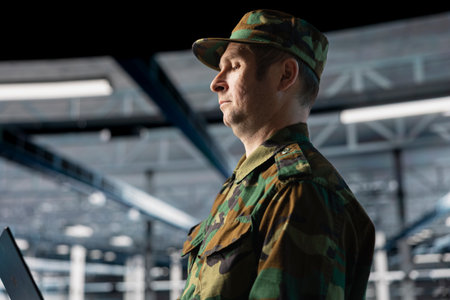 Army information technology expert in data center troubleshooting military computer systems and networks using laptop. Soldier in command center server room using notebook deviceの写真素材