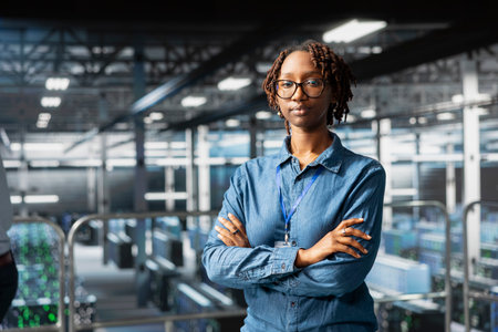 Portrait of smiling african american engineer running diagnostics on AI tools, using deep learning equipment to identify errors. Happy woman working to prevent failure and minimize downtime.の写真素材