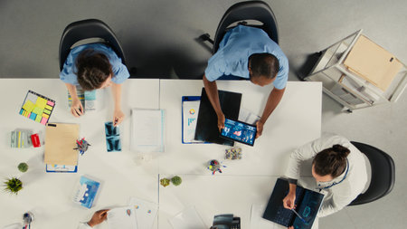 Top down view of surgeons staff in a clinic discussing therapy options and research analysis. The meeting highlights professionalism and innovation in healthcare planning.の写真素材