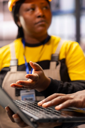 Smart factory engineers oversee an advanced production line in industry 4.0 facility. Professional technicians using laptop, discussing automation, digital maintenance and industrial optimization.の写真素材