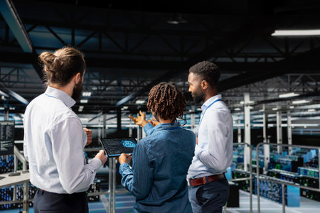Server farm coworkers overseeing work done reviewing neural network code and LLM visualization for datasets. Team of technicians monitoring AI system performance, industrial platform.の写真素材
