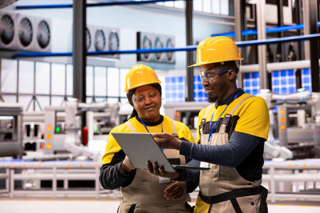 African american engineers at smart manufacturing plant analyzing automated production systems using...