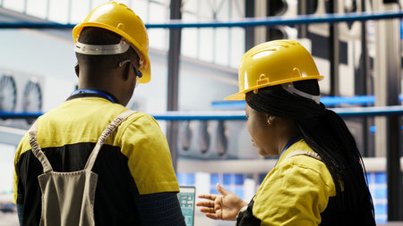 Smart factory engineering team using laptop to analyze IoT sensors data, refining equipment...