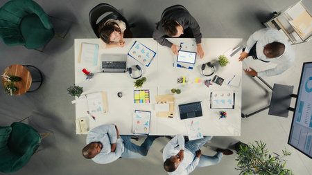 Top down view of conference with investors group discussing performance reports, insights and planning. Professional team evaluates financial data and forecasting for targets.の写真素材