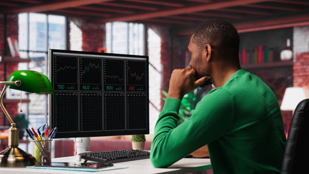 Cheerful day trader gaining money via stock market exchange, maximizing profits by following forex trends and candle stick charts. Thrilled african american broker investor. Camera A.の写真素材