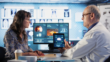 Meeting between doctor and patient to examine MRI scan showing a tumor, exploring treatment options,...
