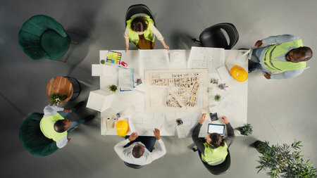 Top down view of development team consulting on real estate investment and construction strategy. Office features 3D models and documents illustrating modern property design concepts.の写真素材