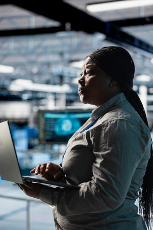 Woman in server farm using laptop, automating system diagnostics using machine learning predictions....