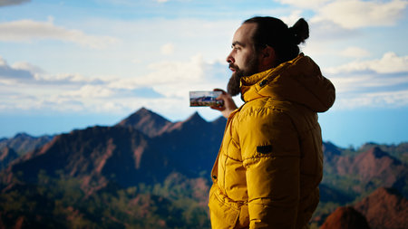 Hiker adventure seeker captures the breathtaking scenic view at the top of mountain, gazes at a...