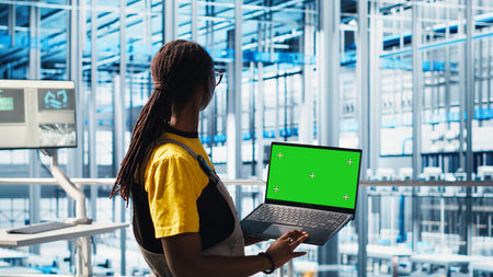 Smart factory technician manages robotic arms using mockup notebook, close up. Engineer in industry...