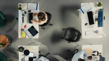 Top down view of work team engaged in negotiation consulting during business meeting. Employees use laptops to analyze finance data and performance reports in office.の写真素材