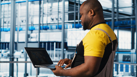 Industry 4.0 industrial plant specialist designs new robotic machines using CAD software on laptop. Smart factory technician using notebook to do tooling for automation equipment, camera A close upの写真素材